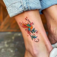 a woman's foot with a colorful bird tattoo on it