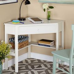 a white desk with a laptop on it and some flowers in a vase next to it