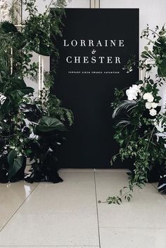 the entrance to lorraine chester is surrounded by greenery and white flowers in black vases