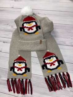 a knitted penguin hat and scarf on a white wooden background