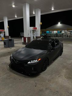 a black car parked in front of a gas station