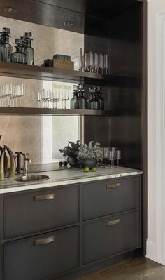 a kitchen with lots of glassware and bottles on the shelves above the counter top