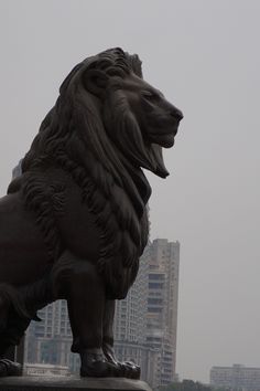 a statue of a lion in front of a city skyline