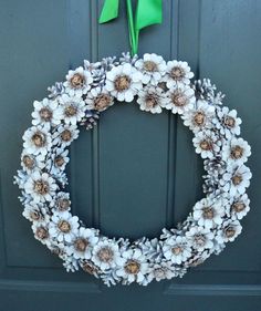 a wreath made out of fake flowers and green ribbon hangs on the front door with a bow