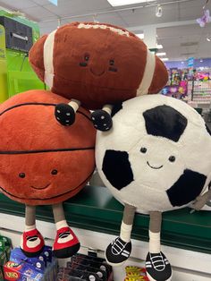 two stuffed animals are sitting on top of each other in a store display case, one is holding a basketball and the other is standing up