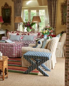 a living room filled with lots of furniture and flowers on the windows sills