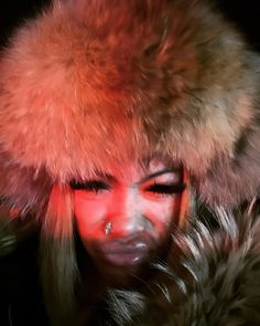 a woman wearing a fur hat with red light coming from her eyes and nose to the side