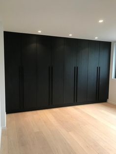 an empty room with black cabinets and hard wood floors