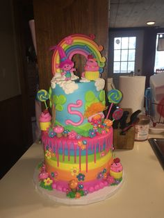 a birthday cake decorated with rainbows and clouds