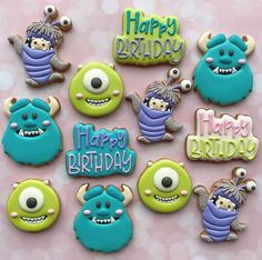 decorated cookies with monsters and happy birthday words on pink tablecloth background, closeup