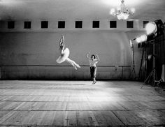 two people are dancing in an empty room with lights on the ceiling and one person is jumping