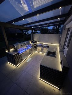 an outdoor kitchen is lit up with leds and under - awning lights at night