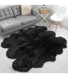 a black sheepskin rug is in the middle of a living room with a gray couch