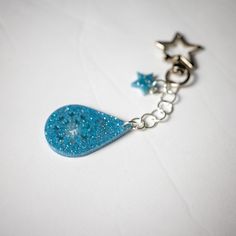 a blue necklace with stars hanging from it's side on a white table top