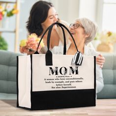 two women sitting on a couch and one is holding a black and white shopping bag