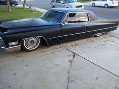 an old black car is parked on the sidewalk