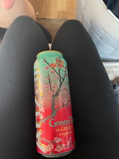 a can of green tea sitting on top of someone's legs