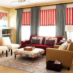 a living room filled with furniture next to a window covered in red and white curtains