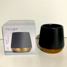 a black and gold vase next to a box on a white countertop with the lid open