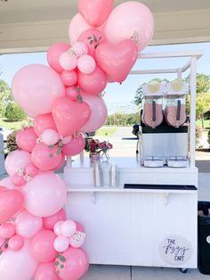 a bunch of pink balloons are hanging from the ceiling near a table with some shoes on it