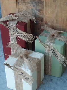 three wrapped gift boxes sitting next to each other with burlocks and twine