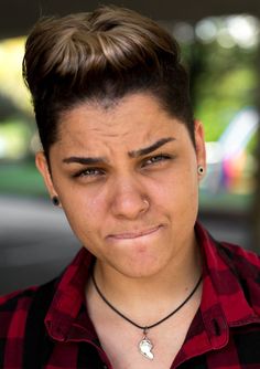 a close up of a person wearing a red shirt with a black and white necklace