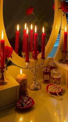 a table topped with lots of candles next to a round mirror on top of a counter