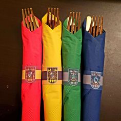 four different colored napkins with gold forks in them and one has a crest on it