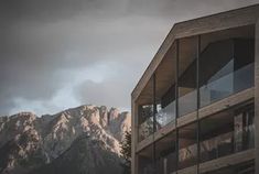 a tall building sitting next to a mountain covered in snow and clouds on a cloudy day