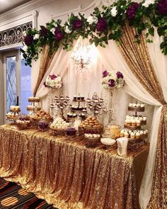 a table topped with lots of desserts under a chandelier filled with flowers