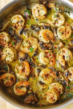 a pan filled with shrimp and mushrooms on top of a wooden table