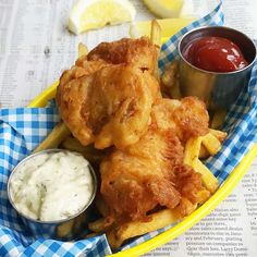 fried chicken and french fries with dipping sauces in a yellow bowl on a newspaper