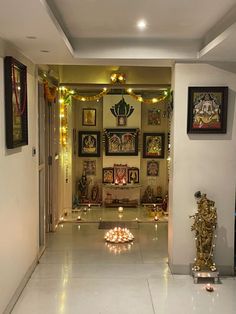 a hallway with lights and pictures on the wall, candles in front of an open door