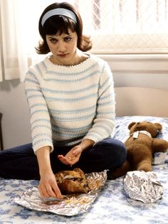 a woman sitting on top of a bed next to a teddy bear and some tin foil