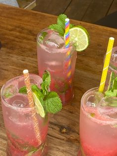 two glasses filled with drinks sitting on top of a wooden table next to each other