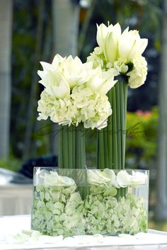 three tall vases with white flowers in them on a table outside at an event