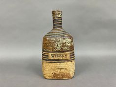 an old fashioned bottle with the word whiskey on it's side sitting on a gray surface