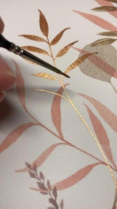 a person cutting out gold leaf designs on a piece of paper with a pair of scissors