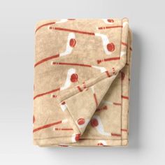 a blanket with baseballs on it is folded in front of a white wall and grey background