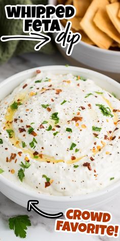 a bowl filled with white dip surrounded by chips