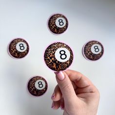 a person is holding up some animal print magnets with the number eight on them