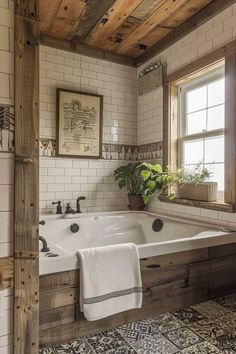 a bathroom with a large white bath tub next to a window and wooden beams on the ceiling