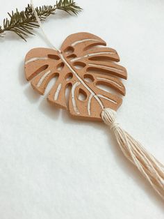 a wooden ornament with a tassel hanging from it's side on a white surface