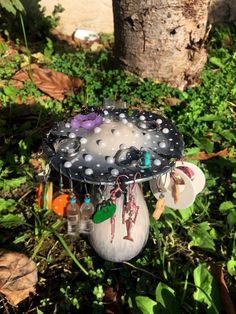 a bird feeder in the grass with beads and charms hanging from it's sides