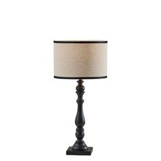 a black lamp with a beige shade on it's side and a white background