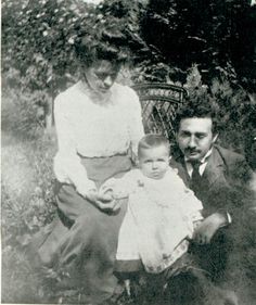 an old black and white photo of two people with a baby in their lap,