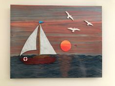 a sailboat floating on top of the ocean with birds flying around it and an orange sun in the background