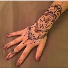 a woman's hand with henna tattoos on it