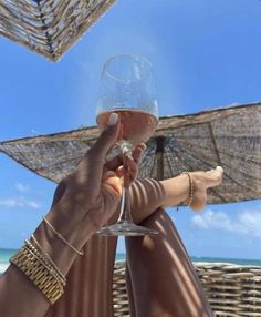 two people toasting with wine glasses in front of an umbrellas on the beach