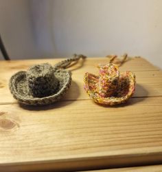 two crocheted hats sitting on top of a wooden table